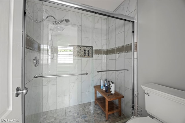 bathroom featuring a shower with shower door and toilet