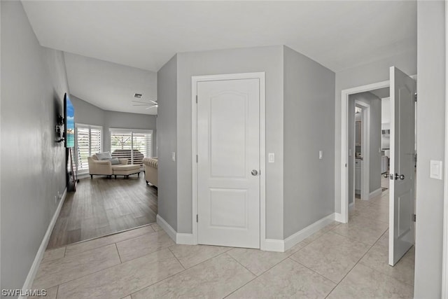 corridor with light tile patterned floors and baseboards