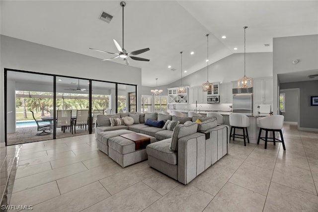 tiled living room featuring high vaulted ceiling, sink, and ceiling fan with notable chandelier