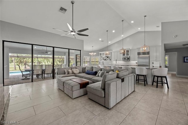 living area with light tile patterned flooring, visible vents, ceiling fan with notable chandelier, and high vaulted ceiling