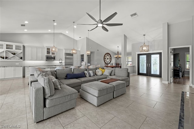 tiled living room featuring high vaulted ceiling, sink, french doors, and ceiling fan with notable chandelier