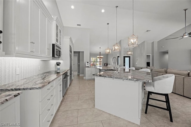 kitchen with ceiling fan with notable chandelier, backsplash, open floor plan, stainless steel appliances, and light tile patterned floors