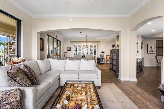 living room featuring wood-type flooring, ornamental molding, and a notable chandelier