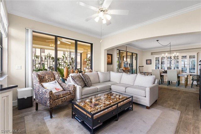 living room featuring crown molding, wood-type flooring, and ceiling fan with notable chandelier