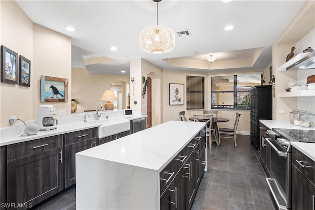 kitchen featuring appliances with stainless steel finishes, pendant lighting, sink, a center island, and a tray ceiling