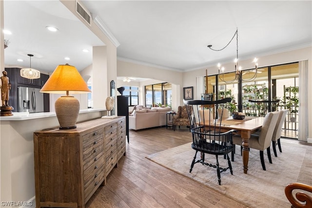 dining space featuring hardwood / wood-style flooring, ornamental molding, and an inviting chandelier