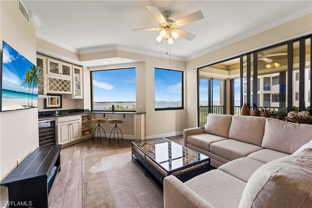 living room with wood-type flooring, wine cooler, bar, ceiling fan, and crown molding