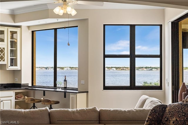 living room with indoor bar, crown molding, ceiling fan, and a water view