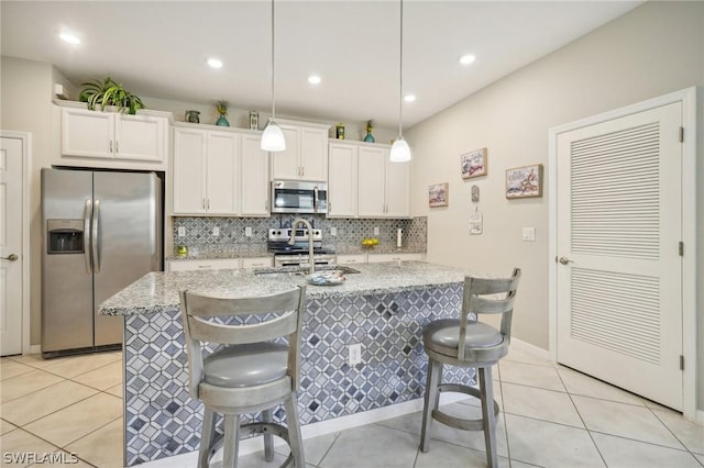 kitchen with light stone counters, a breakfast bar, stainless steel appliances, and decorative light fixtures