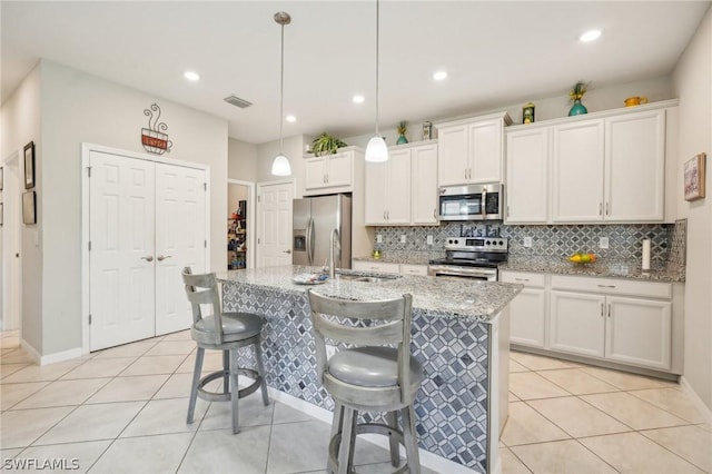 kitchen with stainless steel appliances, sink, pendant lighting, a center island with sink, and white cabinetry