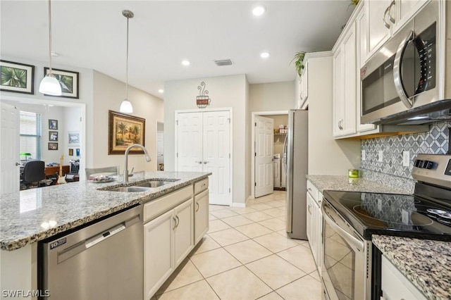 kitchen with white cabinetry, sink, hanging light fixtures, stainless steel appliances, and a kitchen island with sink