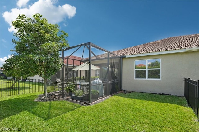 rear view of property with glass enclosure and a yard