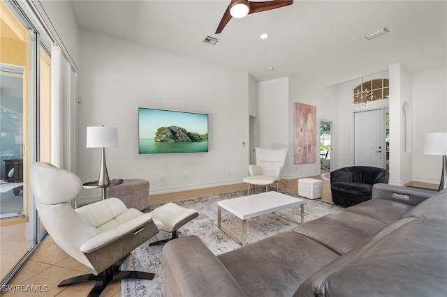 living room featuring ceiling fan with notable chandelier and light tile patterned floors