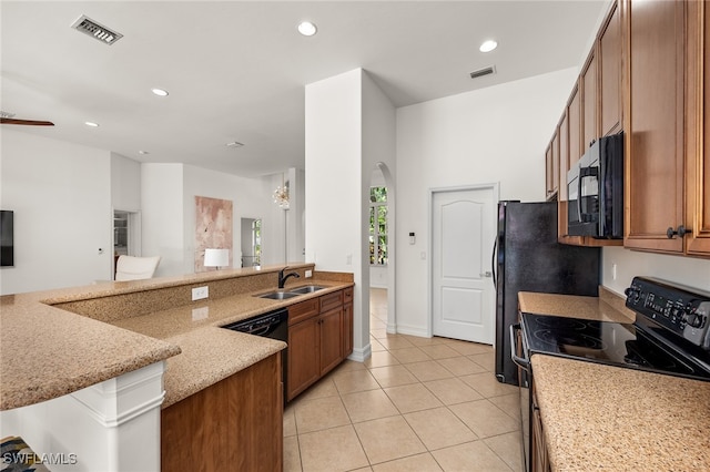 kitchen with kitchen peninsula, light stone countertops, light tile patterned floors, black appliances, and sink