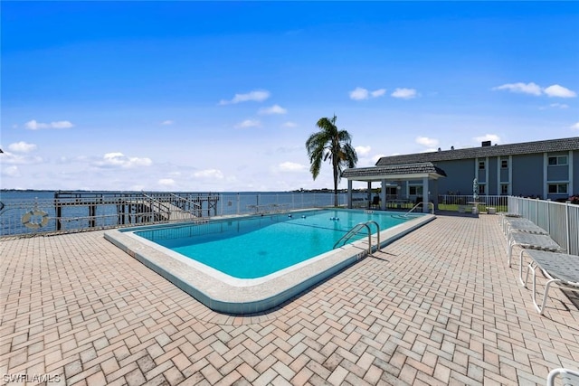 view of swimming pool featuring a patio area and a water view