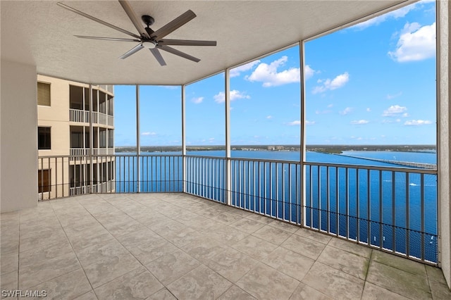 unfurnished sunroom featuring a water view and ceiling fan