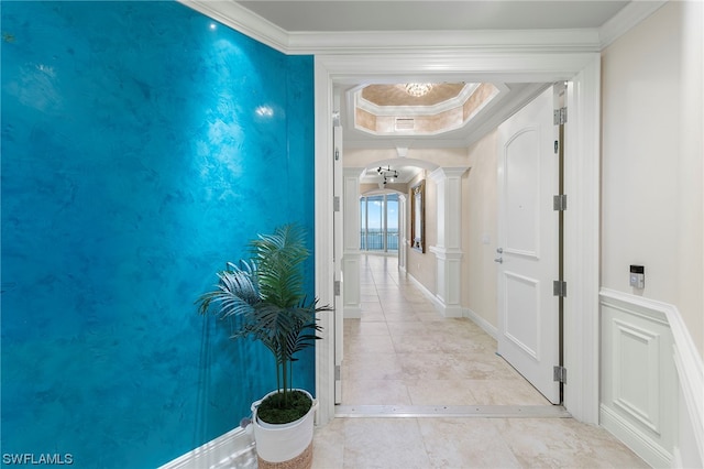 hall featuring light tile floors, crown molding, and ornate columns