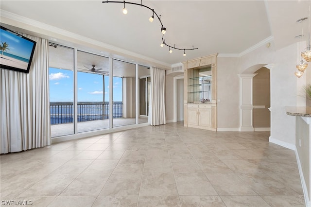 unfurnished living room featuring light tile flooring, ceiling fan, crown molding, track lighting, and ornate columns