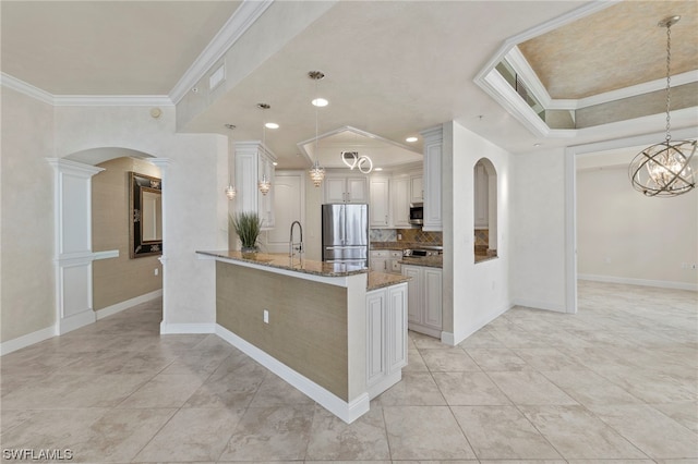 kitchen with crown molding, dark stone countertops, backsplash, stainless steel appliances, and decorative light fixtures