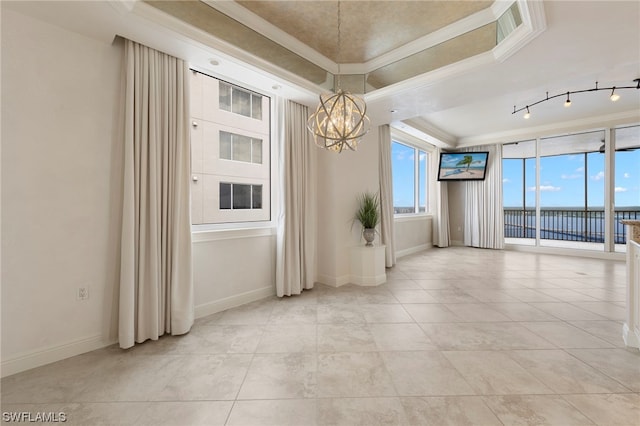 tiled empty room featuring a tray ceiling, a notable chandelier, track lighting, a water view, and crown molding