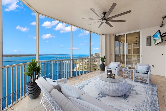 sunroom featuring a water view and ceiling fan