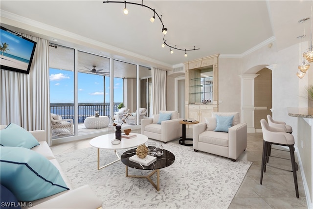 living room featuring ceiling fan, light tile flooring, track lighting, crown molding, and ornate columns