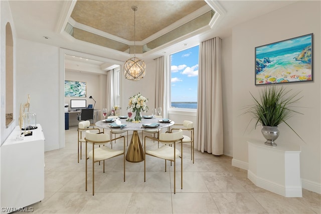 dining room featuring light tile floors, ornamental molding, a water view, a tray ceiling, and an inviting chandelier