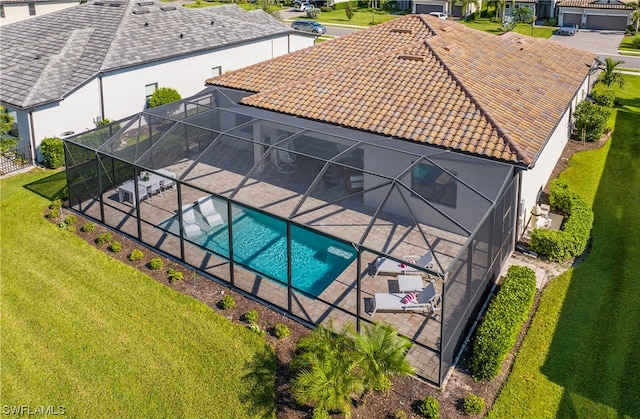 view of pool featuring glass enclosure, a lawn, and a patio