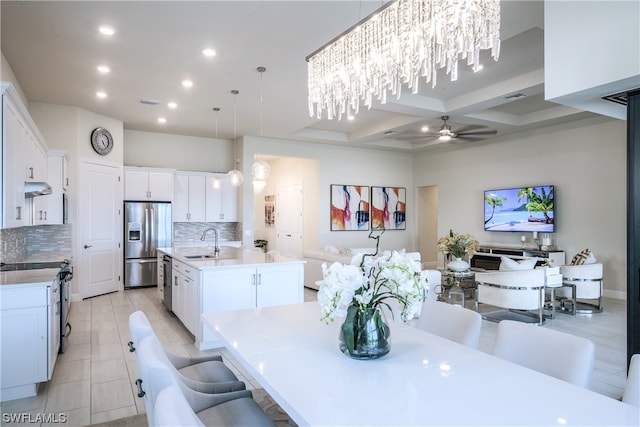 tiled dining room with coffered ceiling, ceiling fan with notable chandelier, sink, and beamed ceiling