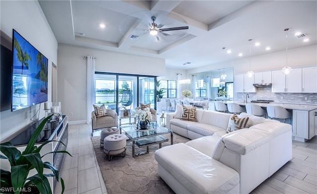 tiled living room with coffered ceiling, plenty of natural light, ceiling fan, and sink