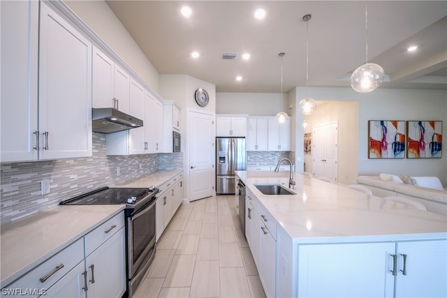 kitchen with stainless steel appliances, white cabinetry, hanging light fixtures, a kitchen island with sink, and sink