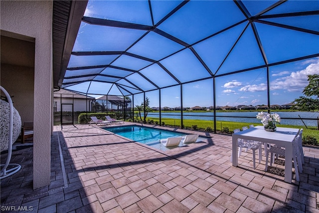 view of pool with glass enclosure, a water view, and a patio