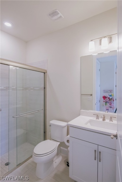 bathroom with toilet, large vanity, a shower with shower door, and tile flooring