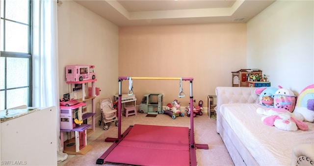 bedroom with light carpet and a raised ceiling