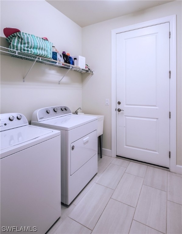 clothes washing area with sink, washing machine and dryer, and light tile flooring