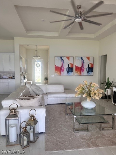 tiled living room featuring a raised ceiling and ceiling fan