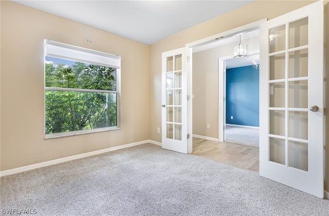 carpeted spare room featuring french doors