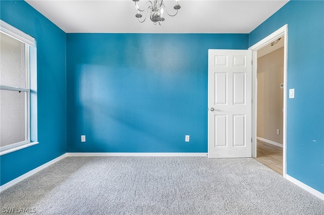 carpeted empty room featuring a chandelier