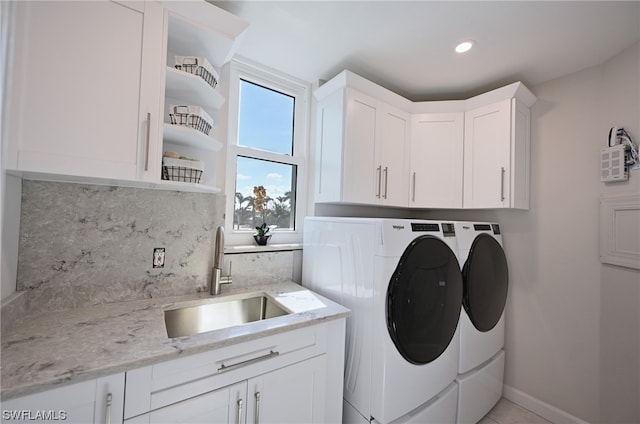 washroom featuring washing machine and dryer, cabinets, and sink