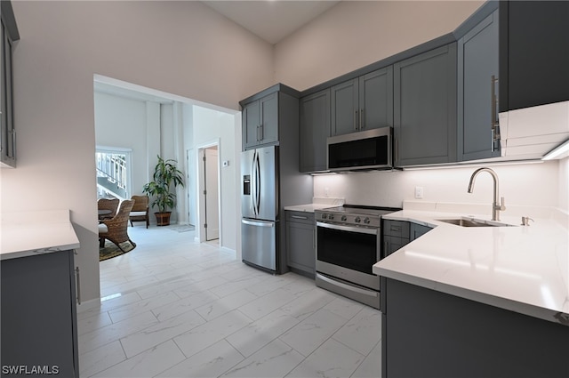 kitchen featuring light tile floors, gray cabinets, sink, and stainless steel appliances