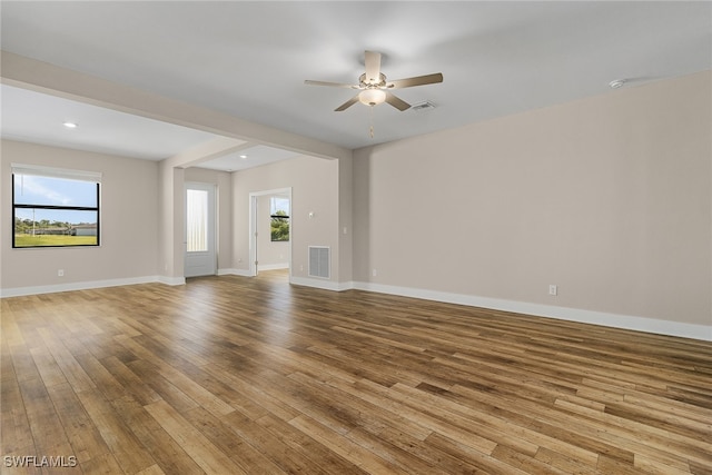 unfurnished living room with ceiling fan, a healthy amount of sunlight, and light wood-type flooring