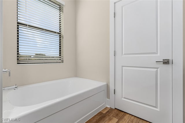 bathroom featuring a healthy amount of sunlight, a bathing tub, and hardwood / wood-style floors