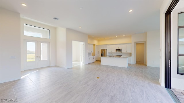 unfurnished living room with french doors and light tile patterned floors