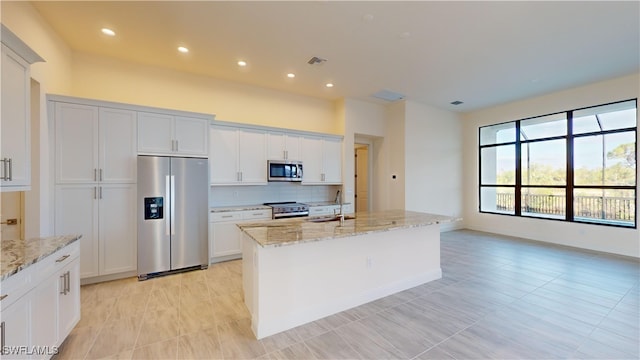 kitchen featuring a kitchen island with sink, white cabinets, sink, light stone countertops, and appliances with stainless steel finishes