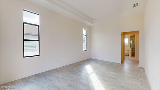 tiled spare room with a raised ceiling