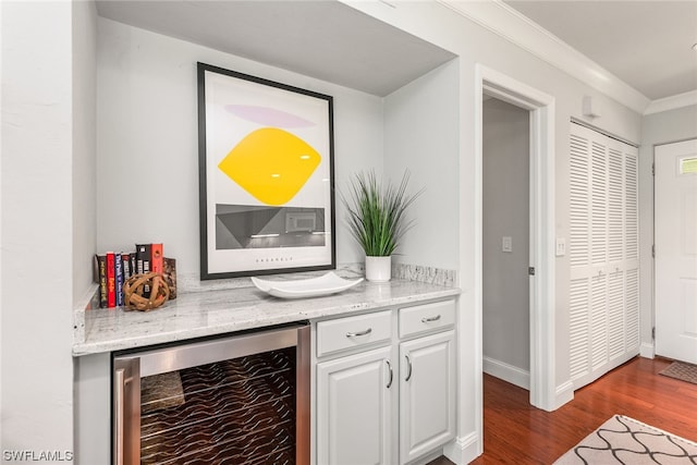 bar featuring light stone countertops, ornamental molding, white cabinets, hardwood / wood-style floors, and wine cooler