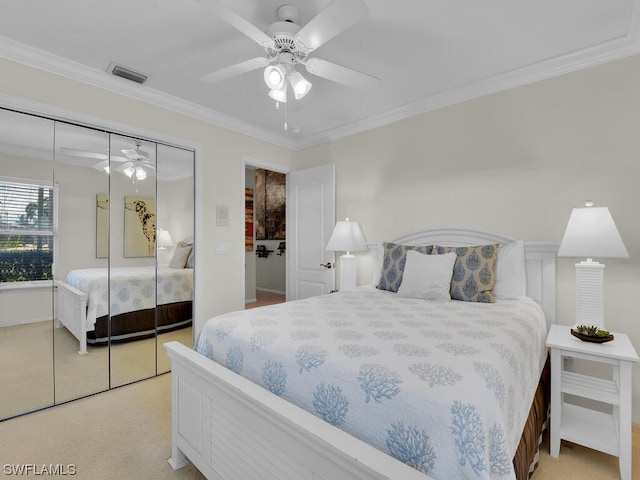bedroom featuring a closet, light carpet, ceiling fan, and ornamental molding
