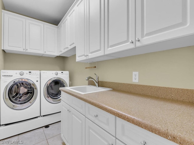 laundry area with light tile flooring, separate washer and dryer, cabinets, and sink