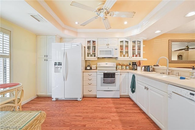 kitchen featuring white cabinetry, a raised ceiling, white appliances, light wood-type flooring, and sink