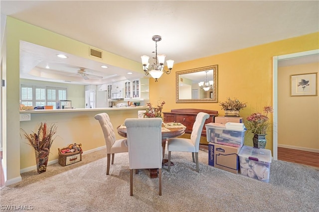 dining area with ceiling fan with notable chandelier, carpet floors, and a tray ceiling